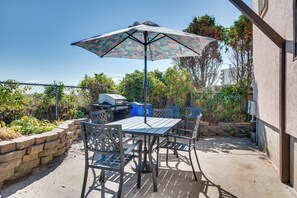 An outdoor patio with a table and chairs, a grill, and a patterned umbrella. - 'beachfront 9' Condo on Old Orchard Beach (Old Orchard Beach)