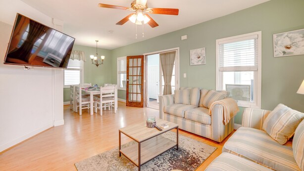 A living room with a sofa, a coffee table, a TV mounted on the wall, a ceiling fan, and a dining area with a table and chairs. - Walk to Ventnor Beach & Boardwalk: Coastal Gem (Ventnor City)