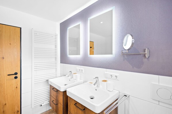A bathroom with two sinks, a mirror, and a towel rack. - Deluxe Suite | Pool, sauna & mountain view (Reit im Winkl)