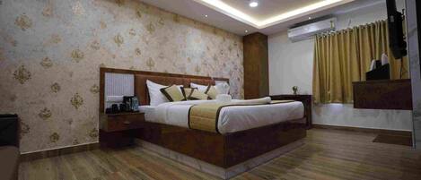 A bedroom with a bed, nightstands, a ceiling fan, recessed lighting, and a television.