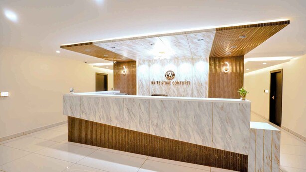 En receptionsdisk med en marmorskiva och trädetaljer, med texten ”WHITE STONE COMFORTS”.
