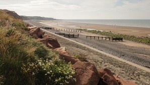 A coastal walkway with a bench, rocky terrain, and a beach in the background. - 1 Cleator Gate (Cleator)