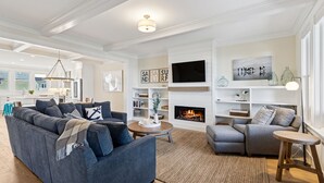 A modern living room with a sectional sofa, a fireplace, and a television. - Seabrook King Tide | Oceanfront, Hot Tub, Pets 4BR | Sleeps 8, Pacific Landing (Pacific Beach)