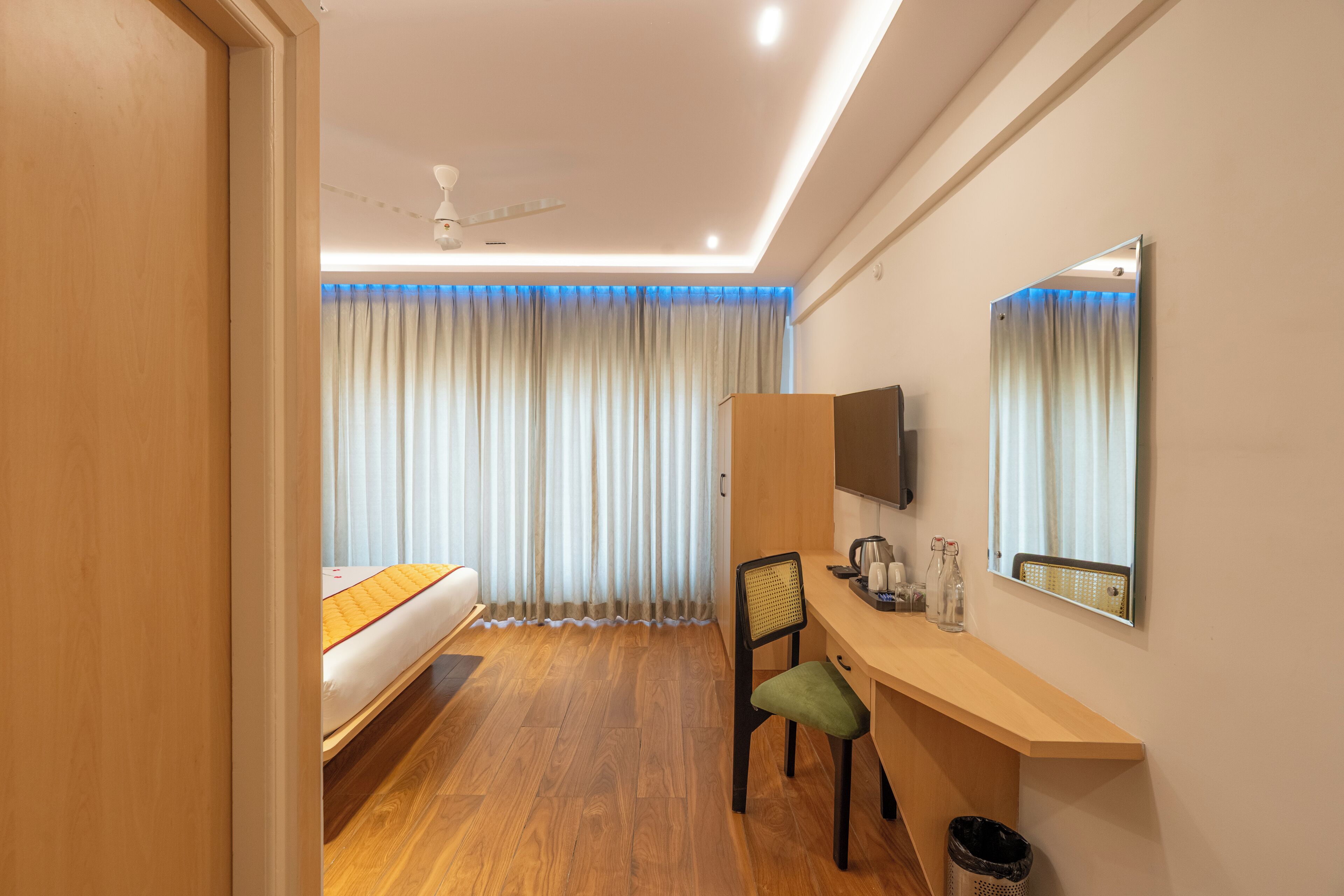 A hotel room with a bed, a desk, a chair, a television, and a window with curtains.