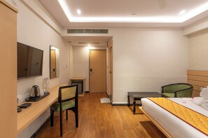 A hotel room with a bed, a desk with a chair, a television, and a mirror.