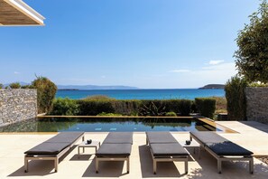 A pool area with lounge chairs and a view of the sea. - Aequora Villa II - Beachfront, 5 min away from the Golden Beach, Infinity Pool (Paros, Cyclades)