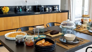 Een ontbijtsetting met croissants, gebak en een koffiemachine.