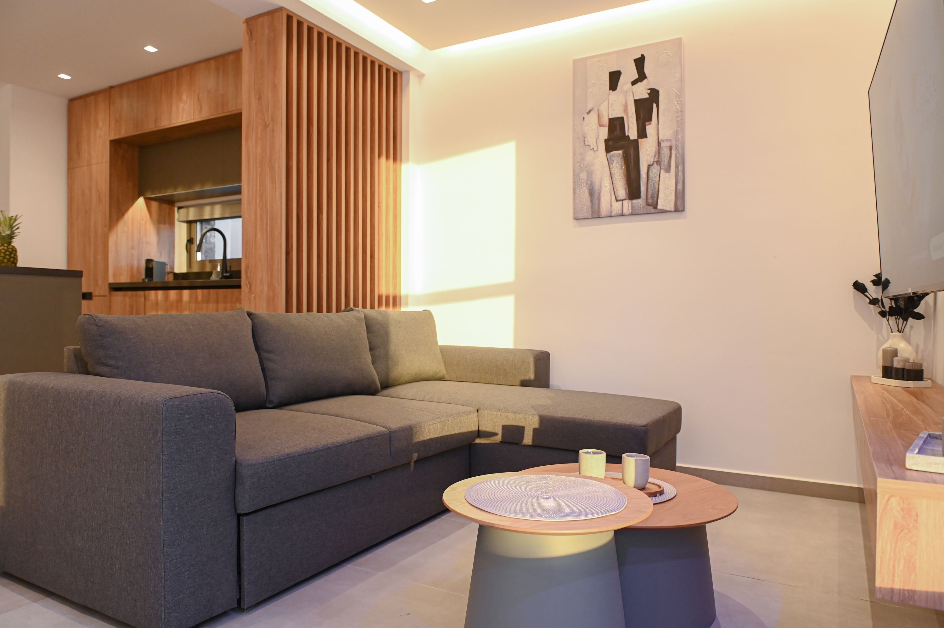 A modern living room with a sectional sofa, a round coffee table, and a wooden accent wall.