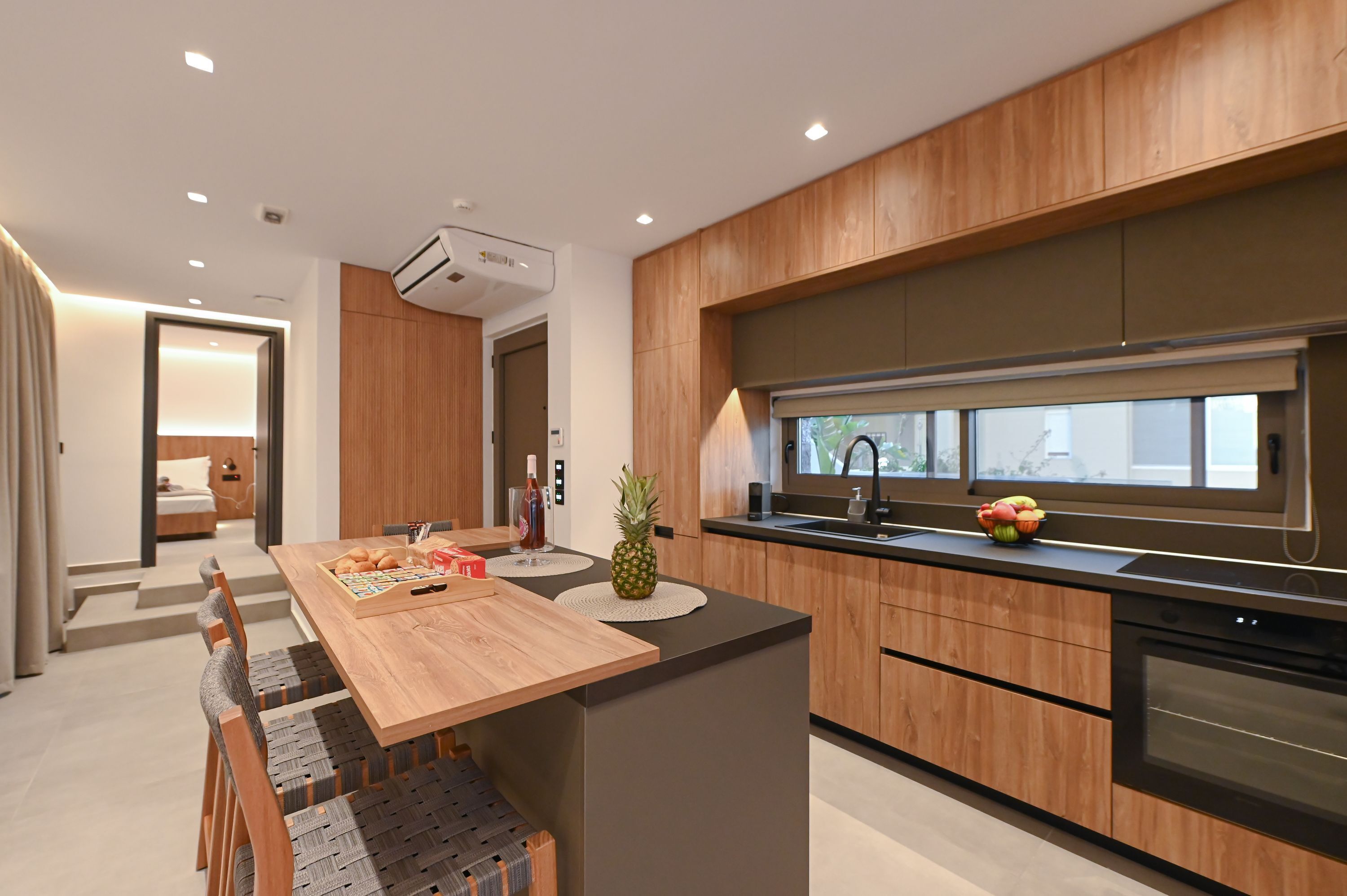 A modern kitchen with wooden cabinets, a built-in oven, and a large window.