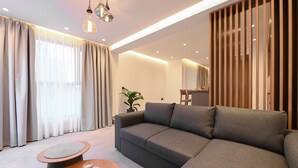 Un salon moderne avec un canapé gris, une petite table en bois sur laquelle sont posées deux tasses, et une plante en pot.