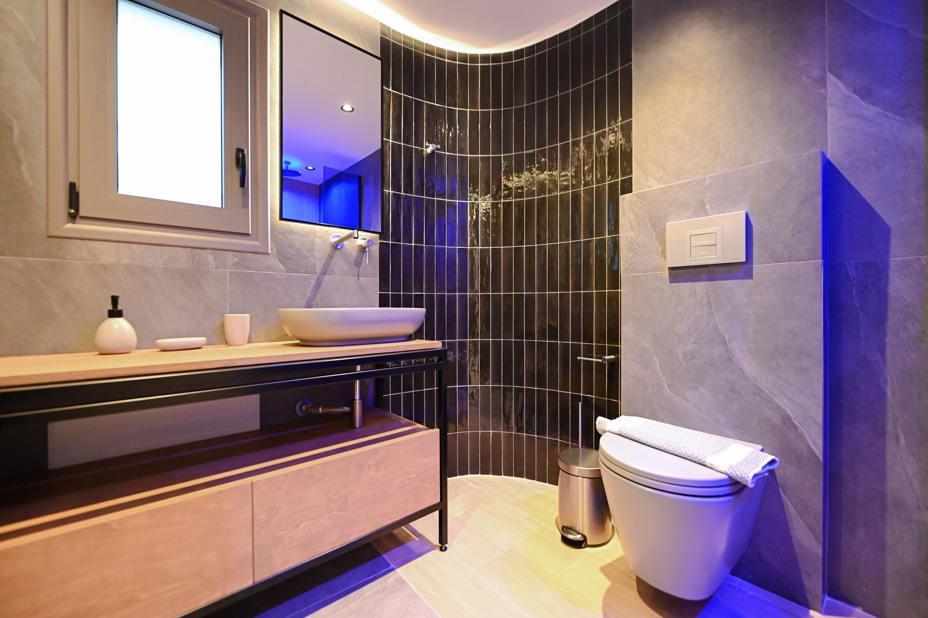 Un bagno moderno con doccia a curva, lavabo a incasso e WC, oltre a uno specchio sopra il lavabo.