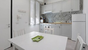 A small, modern kitchen with white cabinets, a white countertop, and a green tray on the table. - Lambrate Flat Milan (Milano)