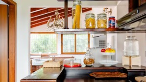 Une cuisine avec un plan de travail en bois, une cuisinière à gaz et divers produits alimentaires rangés sur des étagères.