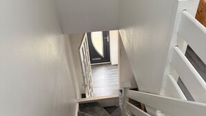 A staircase with white railings and carpeted steps leading to a room with a door and a window. - Close London City Airport- Petok - Free Parking (London)