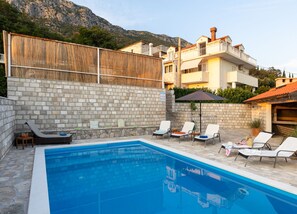 A swimming pool with lounge chairs and a stone wall. - Villa Source with Private Pool (Pridvorje)