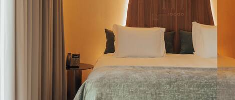 Una habitación de hotel moderna con una cama grande, un panel decorativo de madera y un teléfono sobre una mesita de noche.
