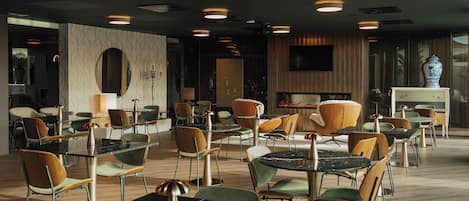 A modern dining area with round tables and chairs, a fireplace, and a television mounted on the wall.