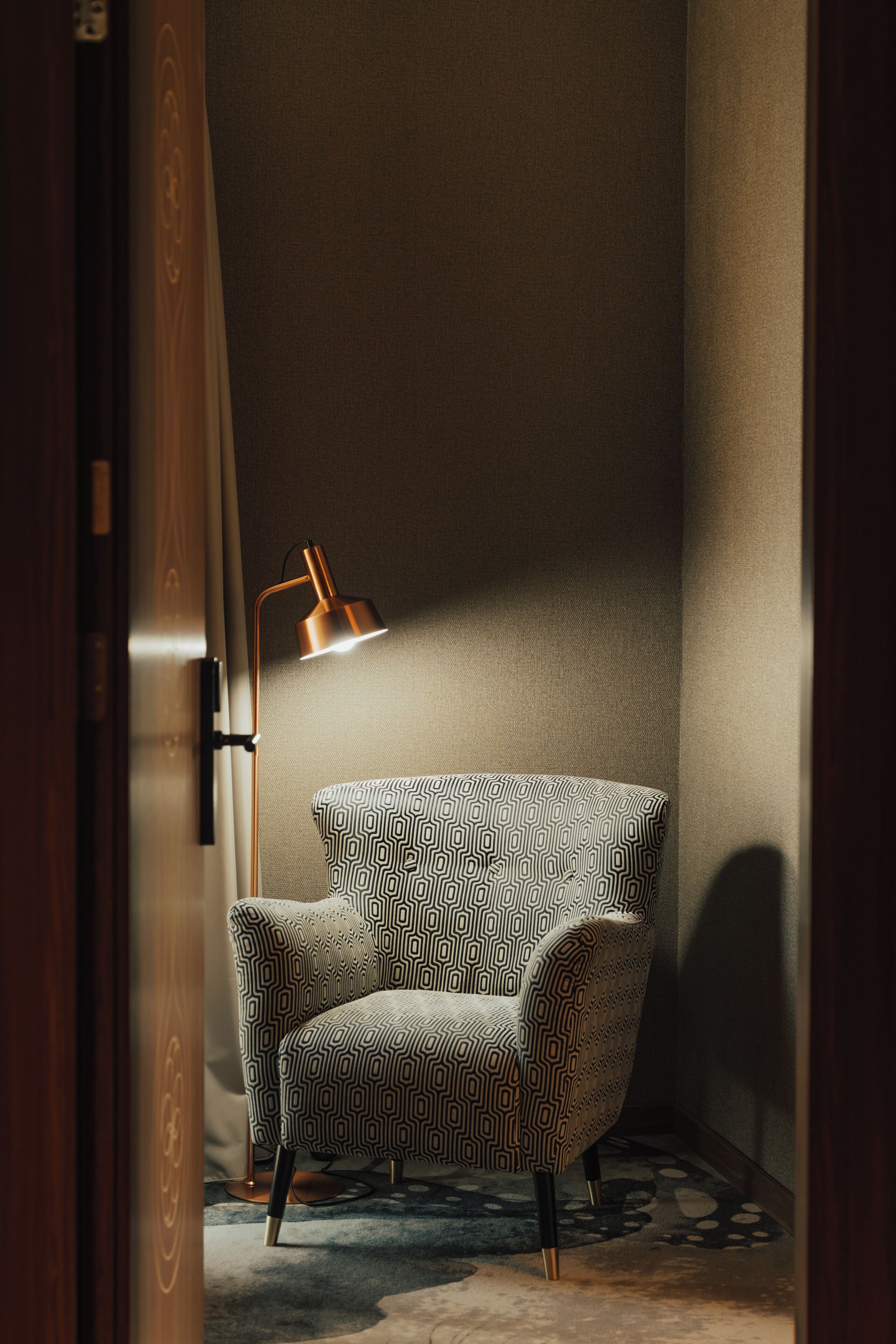 A corner room with a patterned armchair, a floor lamp, and a patterned rug.