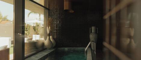A spa area with a pool, wicker furniture, and large vases.