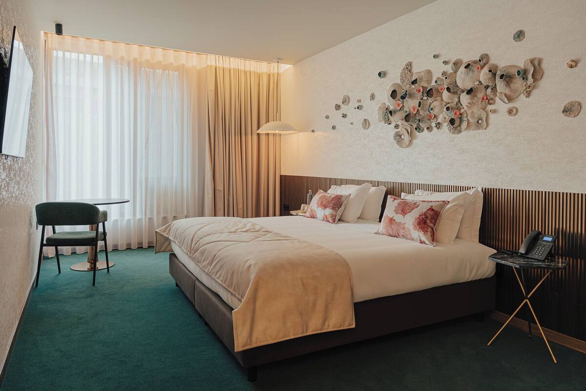 Une chambre d’hôtel avec un lit, une chaise, une lampe et une œuvre d’art murale.