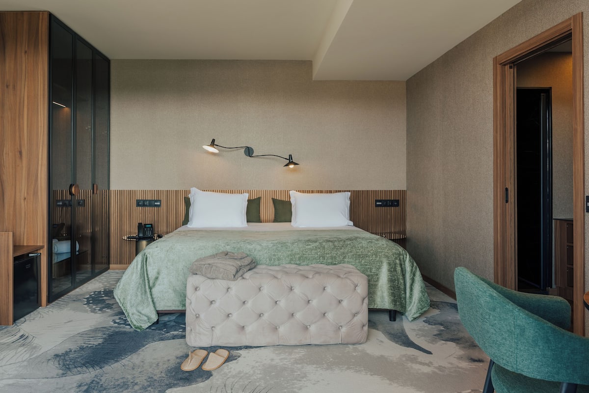 Une chambre à coucher comprenant un lit, des tables de chevet, un banc et une chaise.