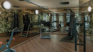 Un gimnasio con equipo de ejercicio, paredes con espejos y suelo de madera.