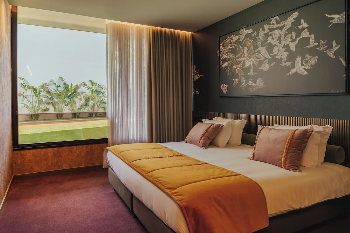 Une chambre d’hôtel avec un grand lit, une vue sur l’extérieur et une œuvre d’art murale.