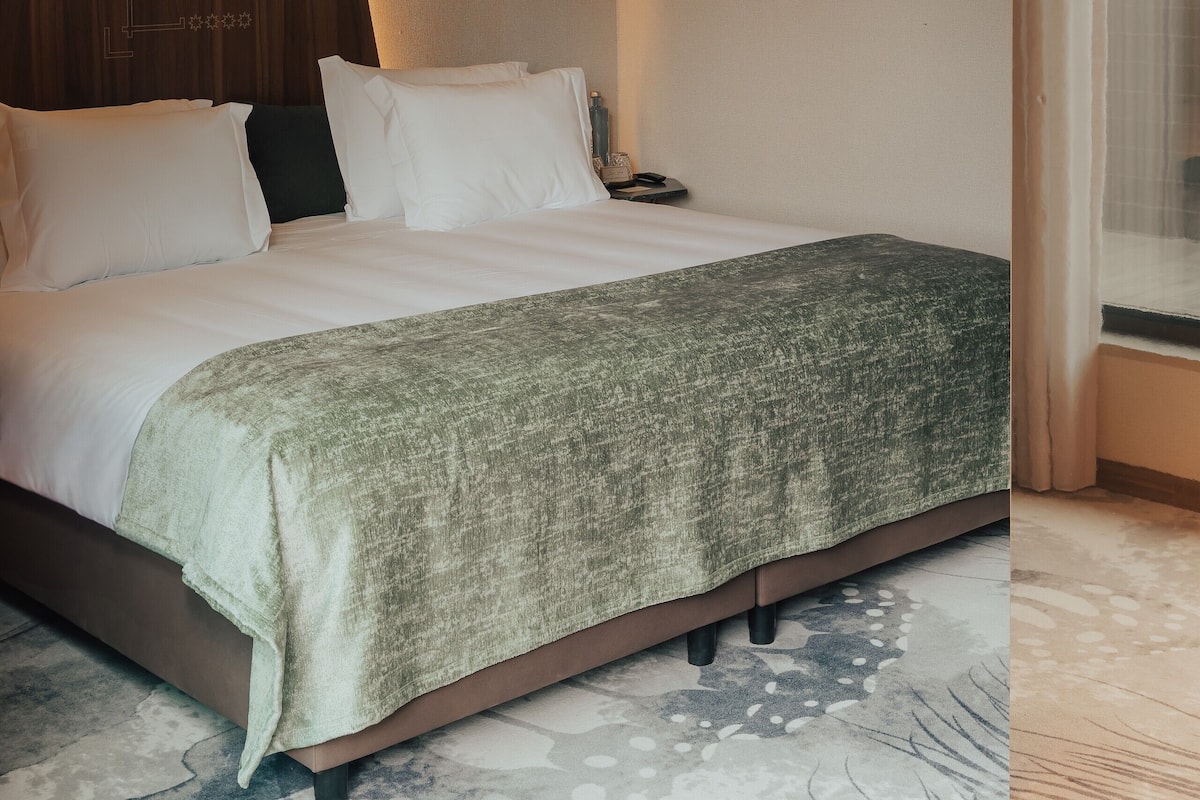 Une chambre à coucher avec un grand lit, des poutres en bois et une fenêtre avec des rideaux.