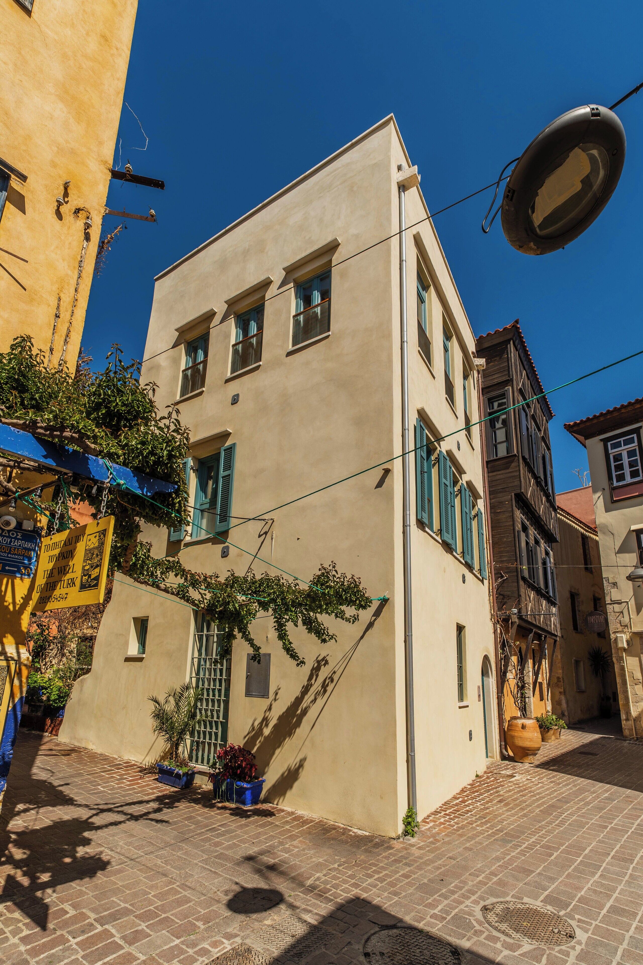 A narrow street with buildings, a blue awning, and a street lamp.