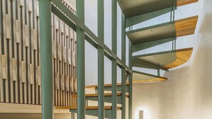A spiral staircase with wooden steps and metal railings, leading to an upper level. - Panaretos Deluxe Maisonette (Chania)