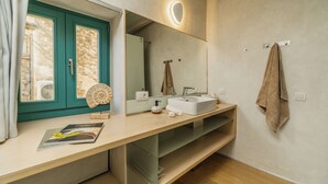 A bathroom with a teal door, a white sink, a mirror with a light, and a towel hanging on the wall. - Panaretos Deluxe Maisonette (Chania)