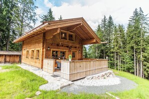 Une cabane en bois dotée d’un balcon, entourée d’une forêt.