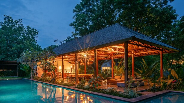 A poolside area with a covered seating area, a pool, and lush greenery. - Experience the Harmony of Luxury, Nature and Wellness! (bali)