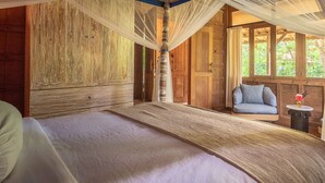 A bedroom with a large bed, wooden walls, a canopy bed, and a view of greenery outside. - Experience the Harmony of Luxury, Nature and Wellness! (bali)