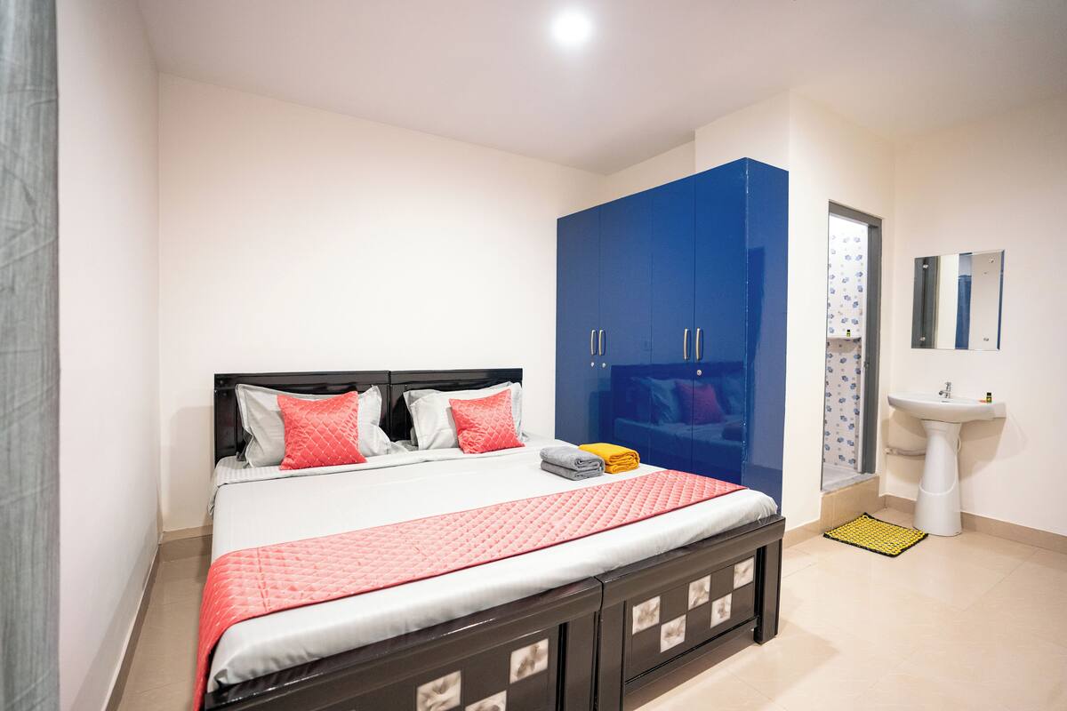 Un dormitorio con cama, armario, lavabo y espejo.