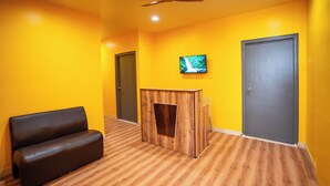A room with a sofa, a wooden cabinet, a television, and two doors. - Yellow Bells Signature (Hyderabad)