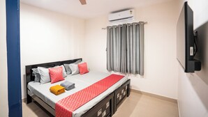 A bedroom with a bed, a ceiling fan, an air conditioner, a TV, and a window with curtains. - Yellow Bells Signature (Hyderabad)