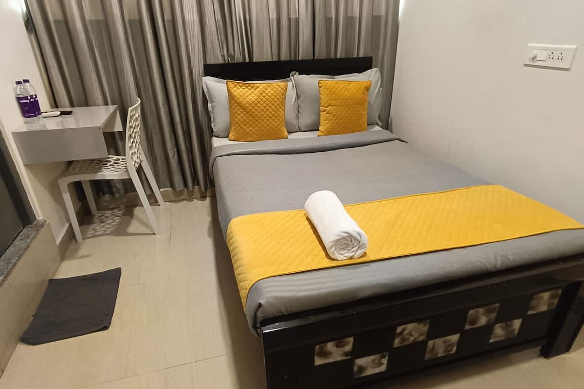 Un dormitorio ordenado con cama, escritorio y silla.