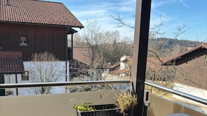 A balcony with a black chair and a small table, potted plants, and a view of neighboring houses. - Komfortables Helles 2-zimmer-appartment (Waldkirchen)