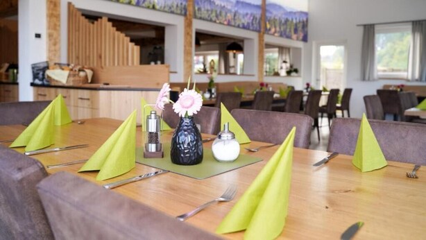A dining area with wooden tables, green napkins, and a vase with flowers. - Komfortables Helles 2-zimmer-appartment (Waldkirchen)