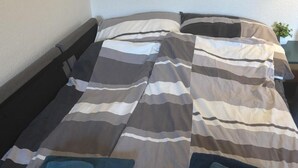A bed with a striped bedspread, two pillows, and a folded towel on each side. - Komfortables Helles 2-zimmer-appartment (Waldkirchen)
