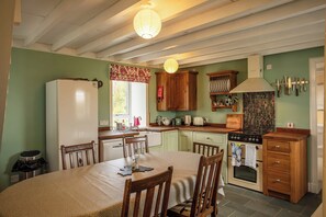 Eine Küche mit Esstisch, Stühlen, Kühlschrank, Backofen und Holzschränken.