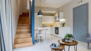 A modern kitchen with white cabinets, a built-in oven, and a blue accent wall. - Cozy villa in Parga. Pet friendly! (Parga)