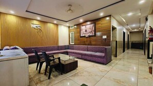 A modern living room with a sofa, a glass coffee table, and a desk. - Hotel Jainam Palace (Ujjain)