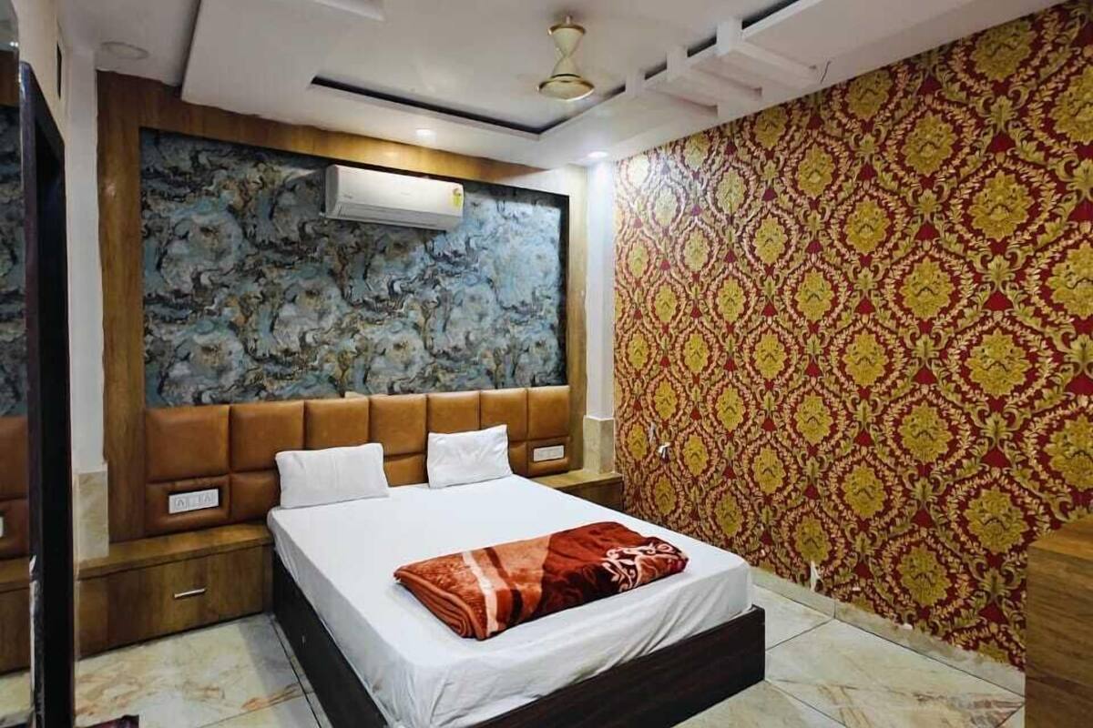 A modern bedroom with a large bed, a headboard with built-in lighting, a marble floor, and a patterned wallpaper.