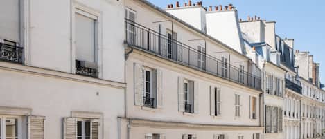 A row of white buildings with shuttered windows and balconies.