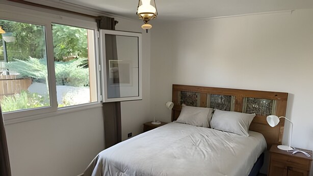 Un dormitorio con cama, mesitas de noche, lámpara de techo y ventana.
