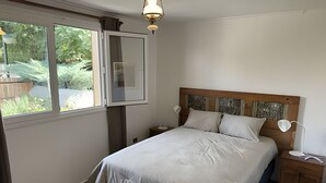 A bedroom with a bed, bedside tables, a nightstand, a window, and a ceiling light fixture. - Oceana Suites Casa Ñuñoa (Santiago)