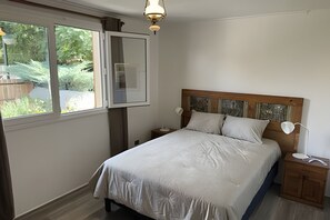 Une chambre à coucher comprenant un lit, des tables de chevet, une commode, une fenêtre et un luminaire au plafond.