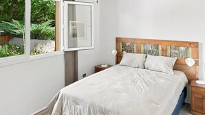 A bedroom with a bed, bedside tables, a window, and a view of greenery. - Oceana Suites Casa Ñuñoa (Santiago)